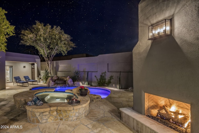 pool at night featuring a patio