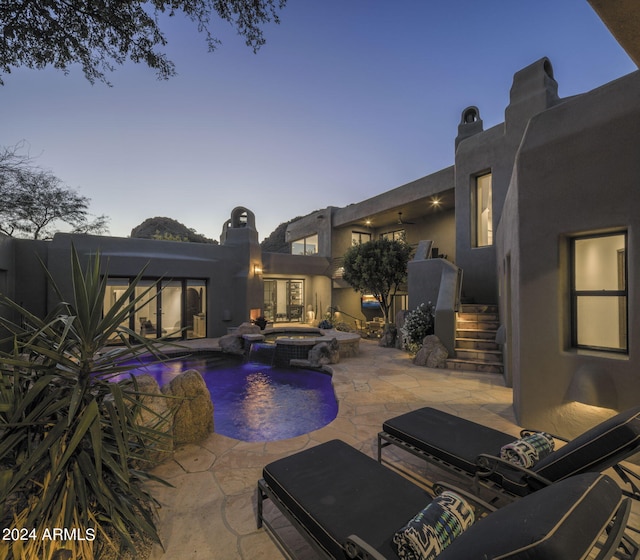 pool at dusk with an in ground hot tub and a patio area