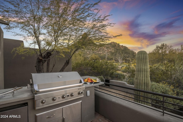 patio terrace at dusk featuring area for grilling and a balcony