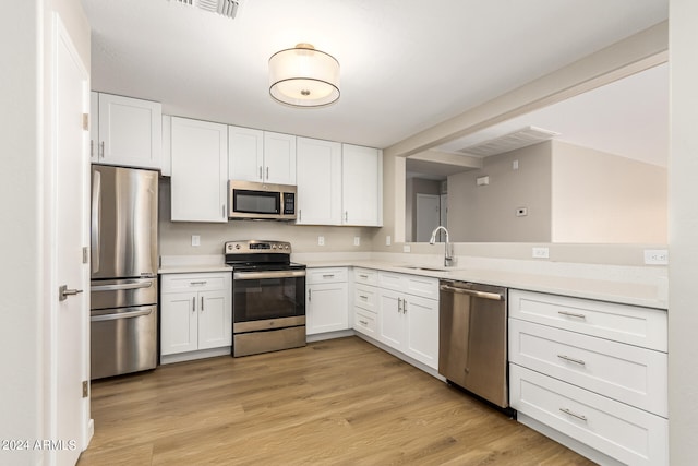 kitchen featuring light hardwood / wood-style floors, appliances with stainless steel finishes, sink, and white cabinetry