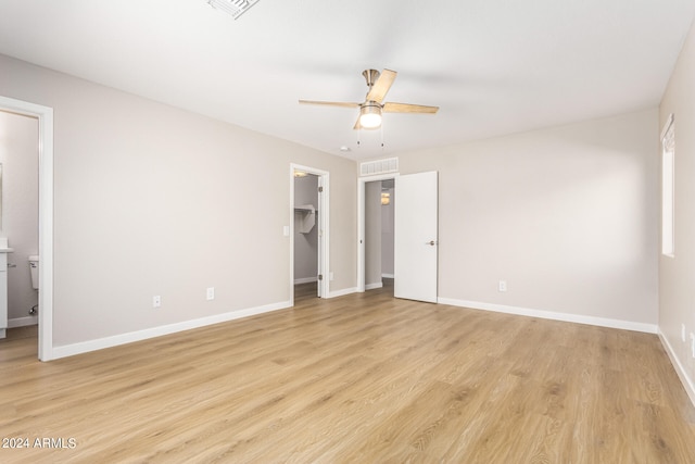 unfurnished bedroom with a spacious closet, ceiling fan, a closet, light hardwood / wood-style floors, and ensuite bathroom