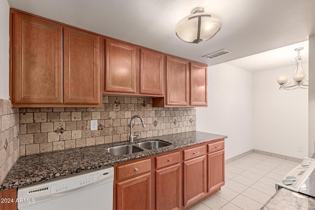 kitchen with backsplash, dishwasher, sink, and dark stone counters