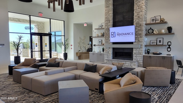 living room featuring a stone fireplace and a towering ceiling