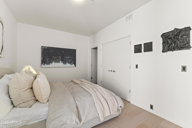 bedroom with light hardwood / wood-style floors and a closet