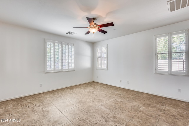 empty room with ceiling fan and a healthy amount of sunlight