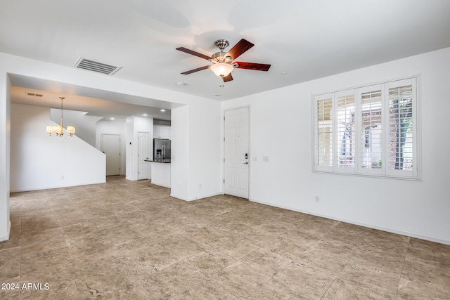 unfurnished living room featuring ceiling fan with notable chandelier