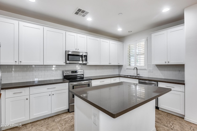 kitchen with backsplash, sink, a center island, white cabinetry, and appliances with stainless steel finishes