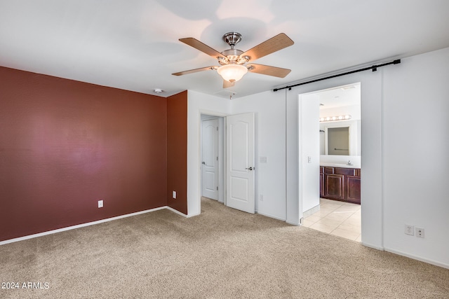 unfurnished bedroom with connected bathroom, light colored carpet, and ceiling fan