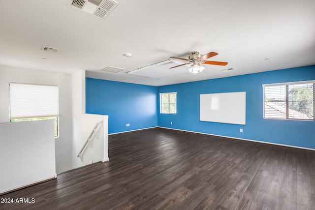 unfurnished room featuring a healthy amount of sunlight, dark wood-type flooring, and ceiling fan