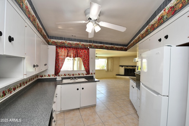 kitchen with dark countertops, light tile patterned flooring, white cabinetry, and freestanding refrigerator