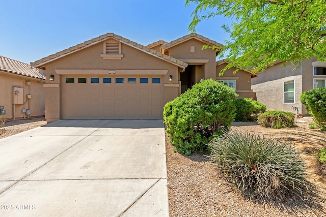view of front of home with stucco siding, driveway, a tile roof, and a garage