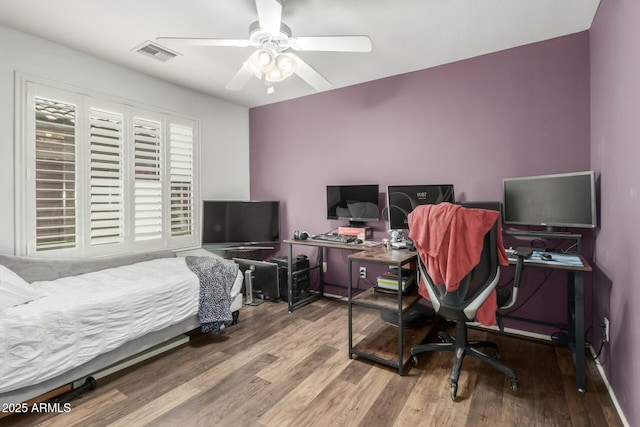 bedroom with ceiling fan, visible vents, and wood finished floors