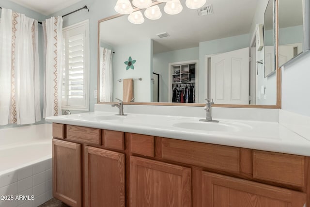 full bath featuring a garden tub, a sink, double vanity, and a spacious closet
