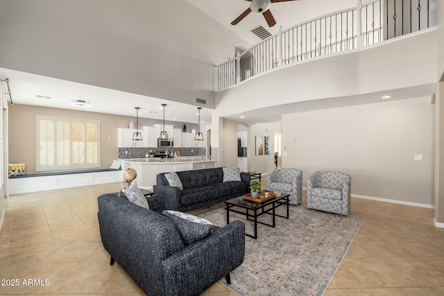 tiled living room featuring ceiling fan and a high ceiling