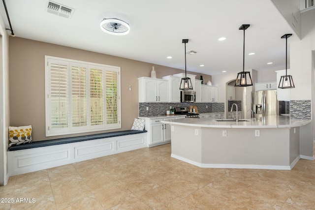 kitchen featuring stainless steel appliances, white cabinetry, tasteful backsplash, and decorative light fixtures