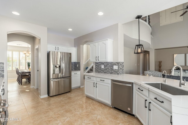 kitchen with appliances with stainless steel finishes, pendant lighting, white cabinetry, sink, and kitchen peninsula