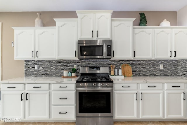 kitchen featuring light stone counters, appliances with stainless steel finishes, backsplash, and white cabinets