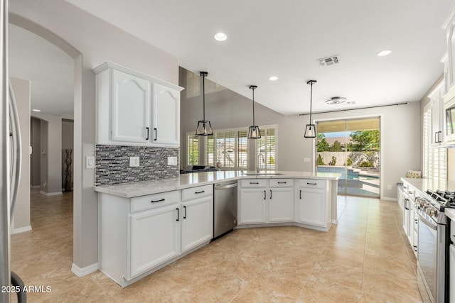 kitchen with appliances with stainless steel finishes, tasteful backsplash, white cabinets, decorative light fixtures, and kitchen peninsula