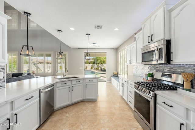 kitchen featuring stainless steel appliances, sink, pendant lighting, and white cabinets