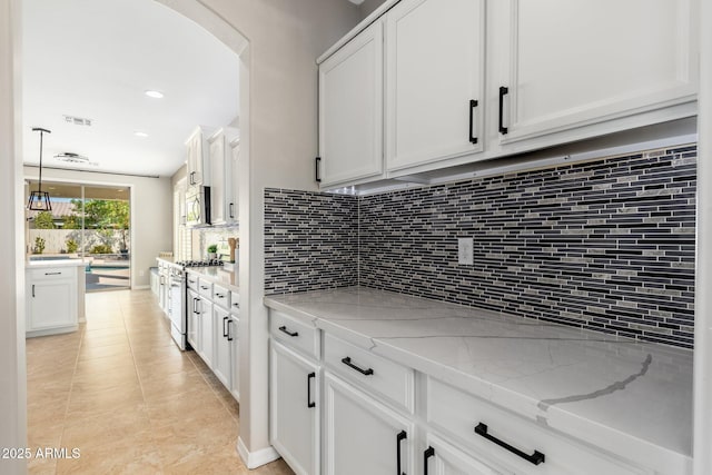 kitchen featuring light tile patterned flooring, appliances with stainless steel finishes, tasteful backsplash, white cabinetry, and light stone countertops