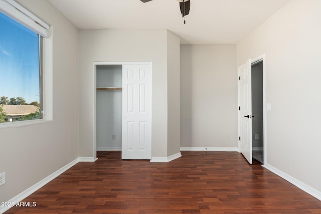 unfurnished bedroom with dark wood-type flooring, ceiling fan, and a closet