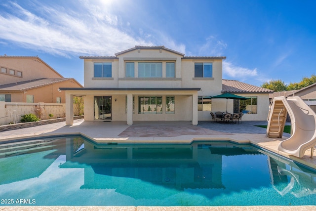 rear view of house featuring a fenced in pool and a patio