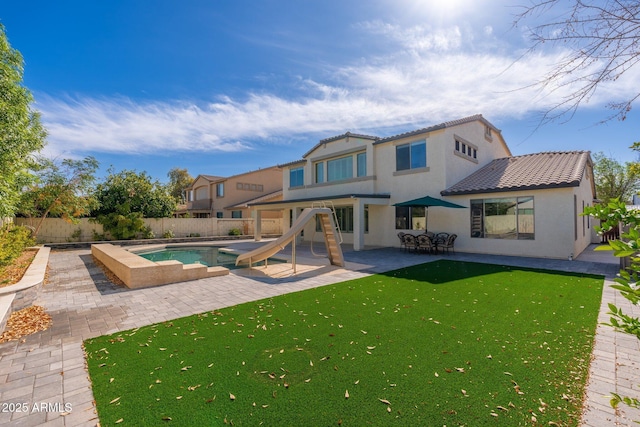 rear view of house with a fenced in pool, a patio, and a yard