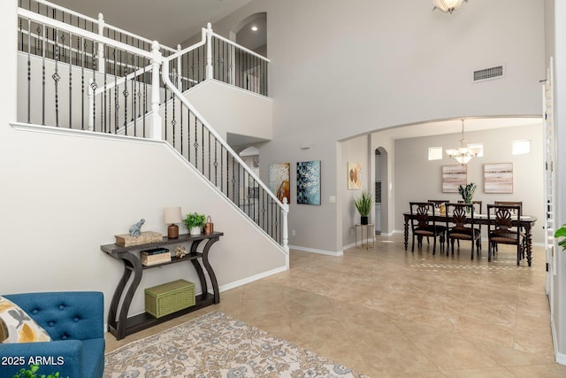 foyer entrance with a towering ceiling, tile patterned floors, and a notable chandelier