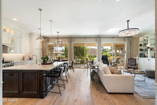 living room with light wood-type flooring, sink, and a chandelier