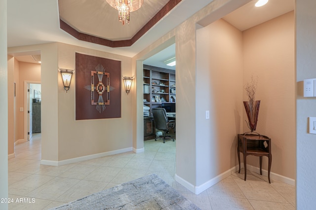 hallway with a raised ceiling, built in features, and light tile patterned floors