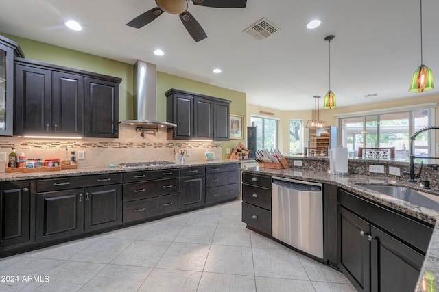 kitchen featuring sink, wall chimney range hood, appliances with stainless steel finishes, and pendant lighting