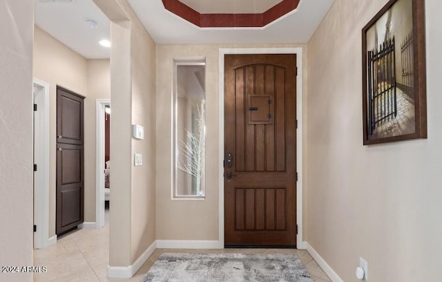 tiled foyer with a tray ceiling