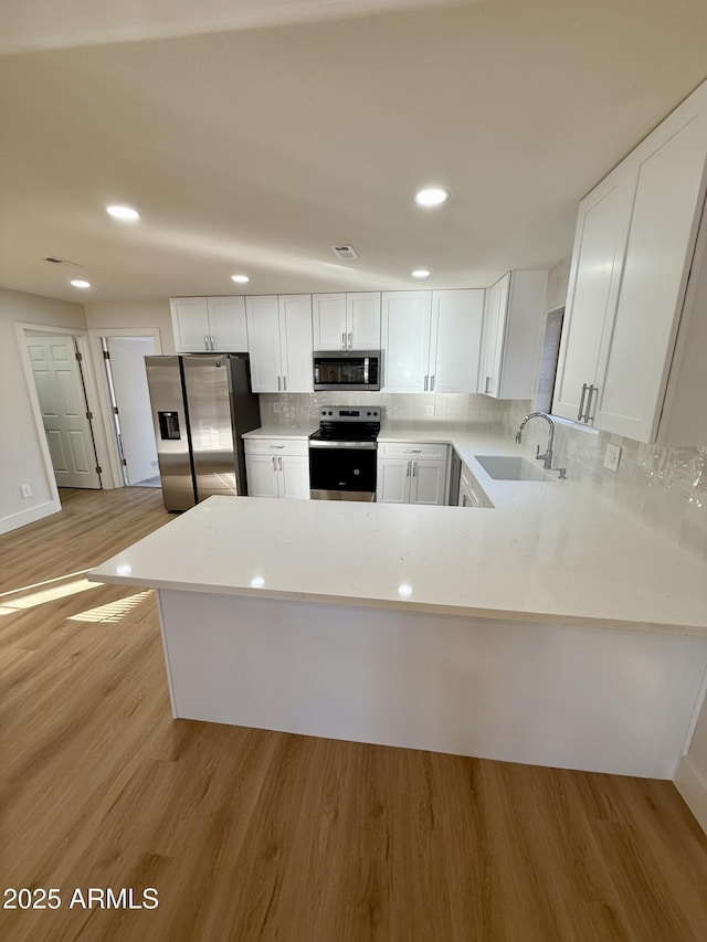 kitchen with stainless steel appliances, light hardwood / wood-style flooring, white cabinets, and sink