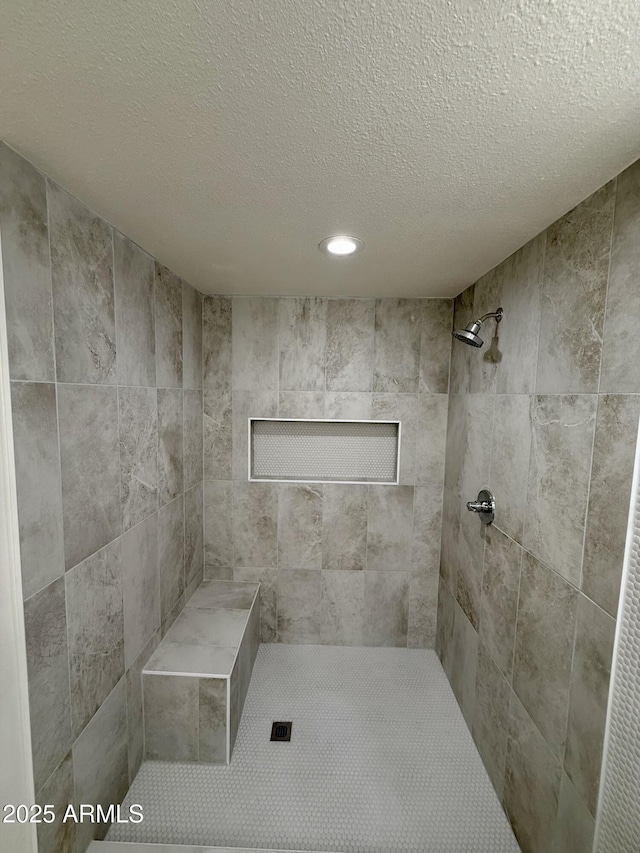 bathroom featuring a textured ceiling and tiled shower