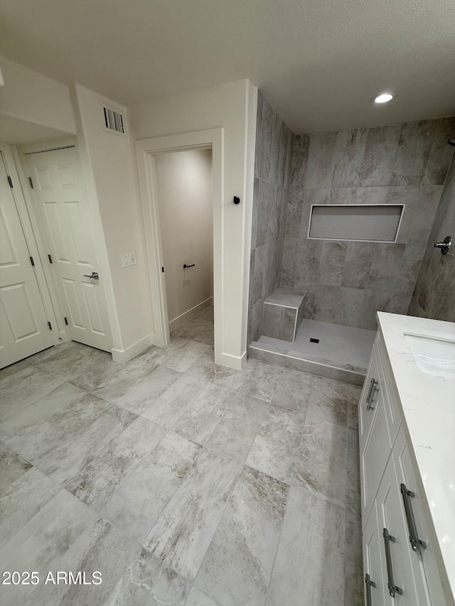 bathroom featuring tiled shower and vanity