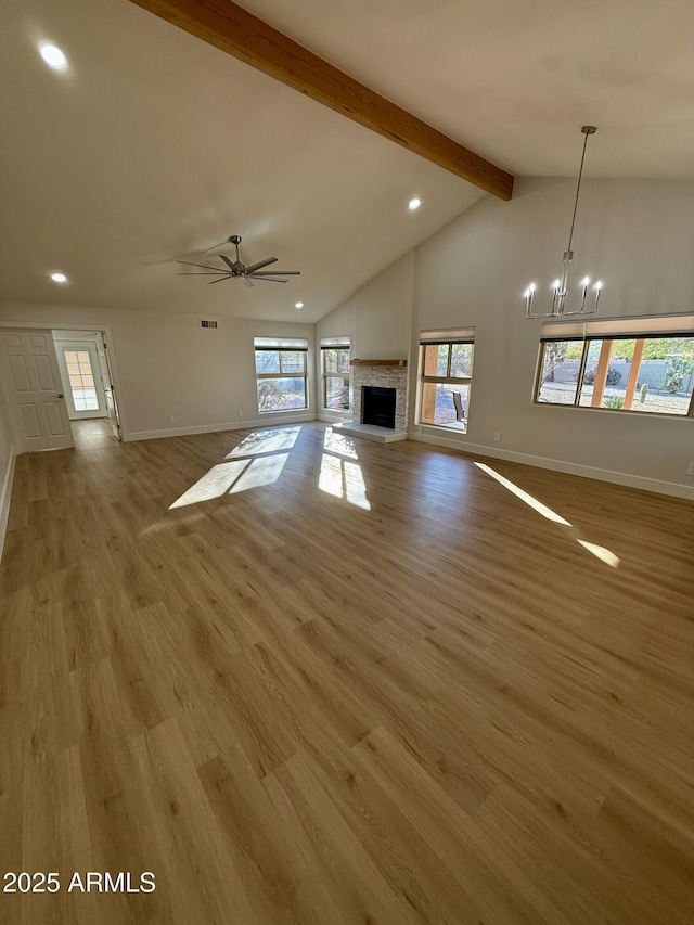 unfurnished living room featuring a fireplace, light hardwood / wood-style floors, ceiling fan with notable chandelier, and vaulted ceiling with beams