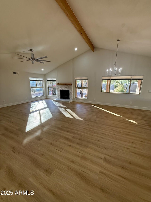 unfurnished living room featuring ceiling fan with notable chandelier, wood-type flooring, high vaulted ceiling, and beamed ceiling