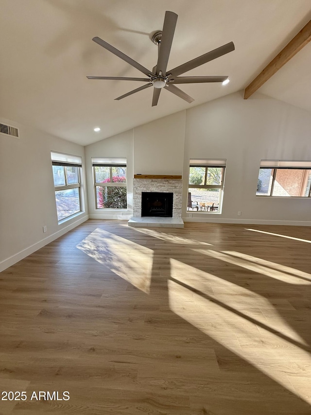 unfurnished living room with ceiling fan, a fireplace, hardwood / wood-style floors, and lofted ceiling with beams