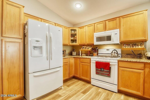 kitchen with vaulted ceiling, light stone countertops, white appliances, and light hardwood / wood-style floors