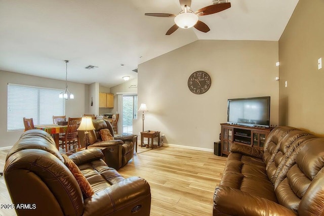 living room with ceiling fan, vaulted ceiling, and light wood-type flooring