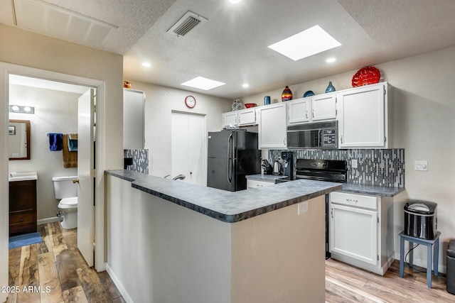 kitchen with white cabinetry, black appliances, kitchen peninsula, light hardwood / wood-style flooring, and backsplash