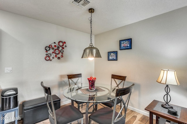 dining space featuring a textured ceiling and hardwood / wood-style floors