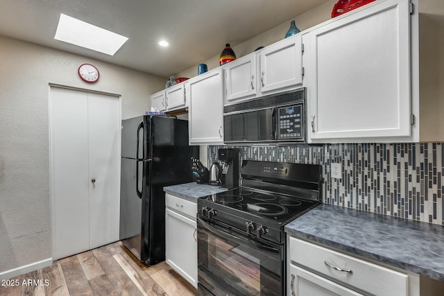 kitchen featuring black appliances, decorative backsplash, light wood-type flooring, a skylight, and white cabinets