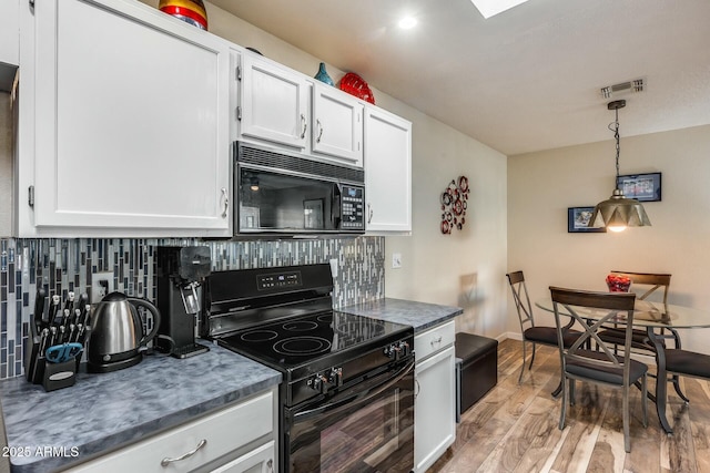 kitchen featuring pendant lighting, black appliances, decorative backsplash, light wood-type flooring, and white cabinetry