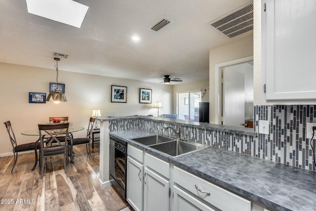 kitchen featuring white cabinets, wood-type flooring, ceiling fan, sink, and backsplash