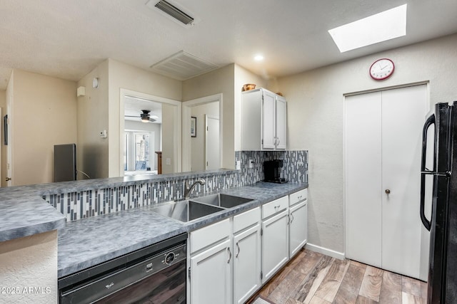 kitchen with light hardwood / wood-style flooring, black appliances, tasteful backsplash, white cabinetry, and sink