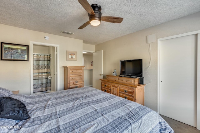 carpeted bedroom with ceiling fan, connected bathroom, and a textured ceiling