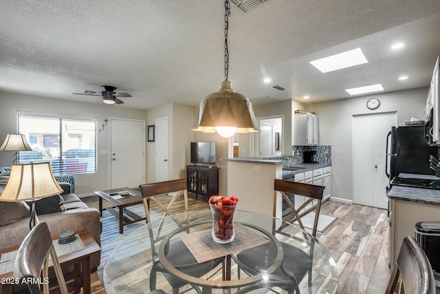 living room featuring ceiling fan, light wood-type flooring, sink, and a textured ceiling