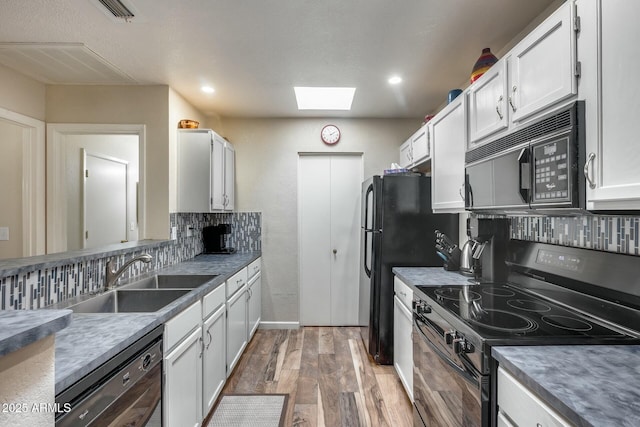 kitchen with sink, white cabinets, a skylight, and black appliances