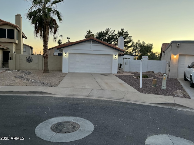 1044 N Arvada N, Mesa, AZ 85205 - view of front of house with a gate, concrete driveway, stucco siding, a garage, and a chimney